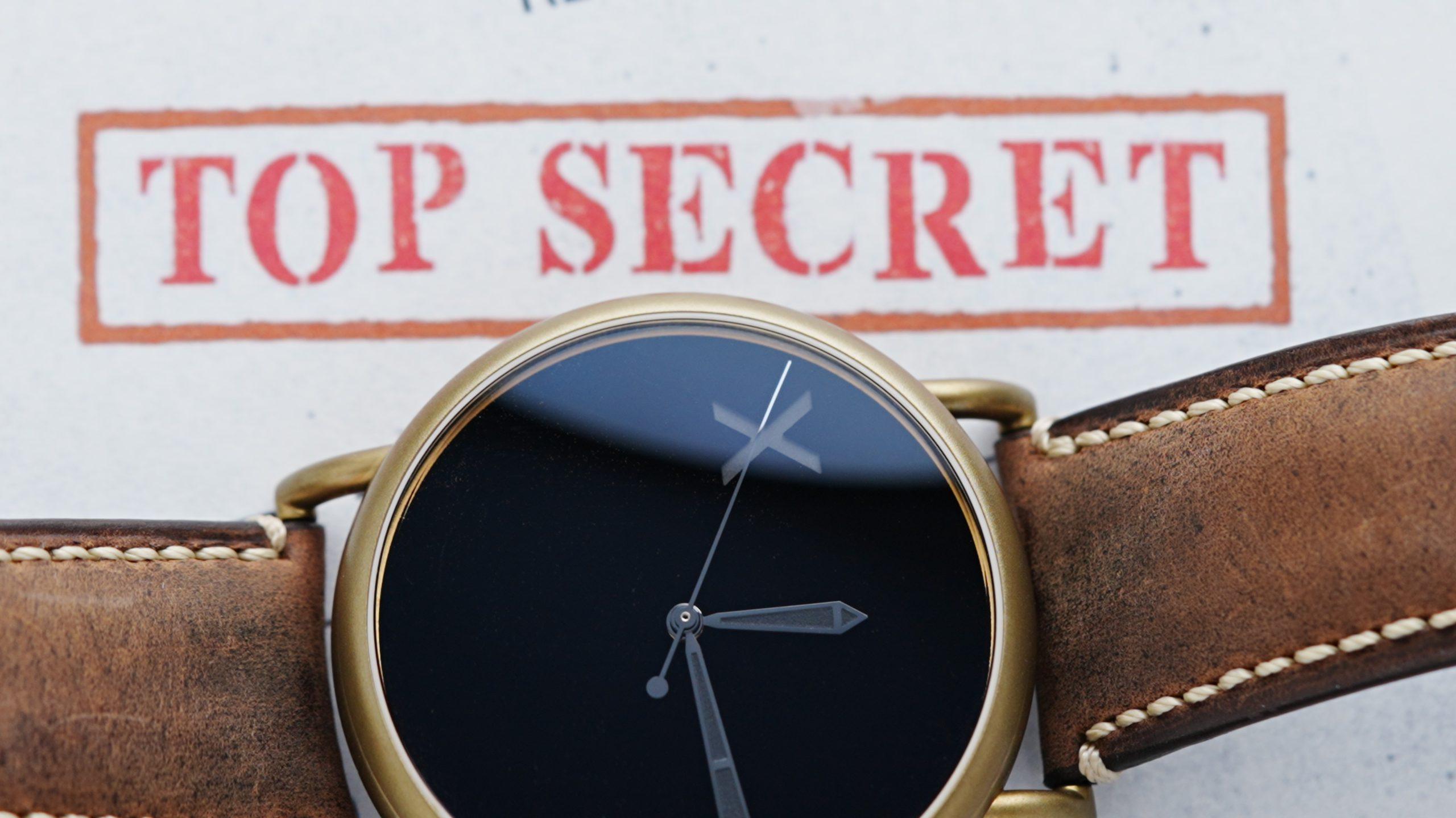 Horizontal shot of the H.Moser & Cie. Confidential Project X Concept Vanta Black in front of TOP SECRECT DOCUMENT.