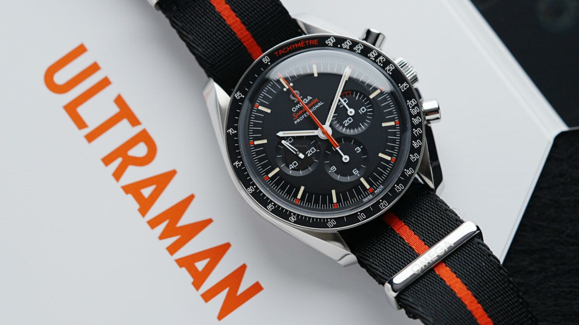 Omega Speedy Tuesday Ultraman watch featured on white background with orange text reading "Ultraman".