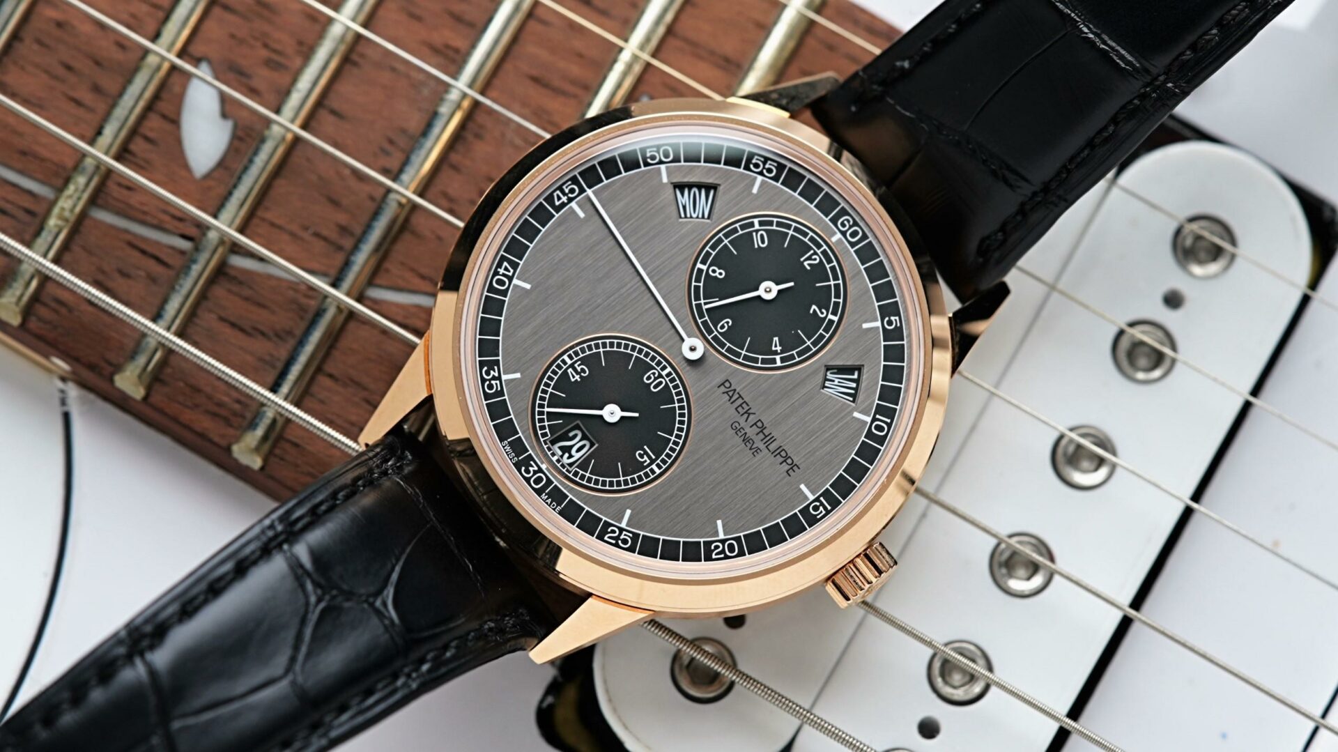Patek Philippe Annual Calendar displayed under white lighting with guitar in background.
