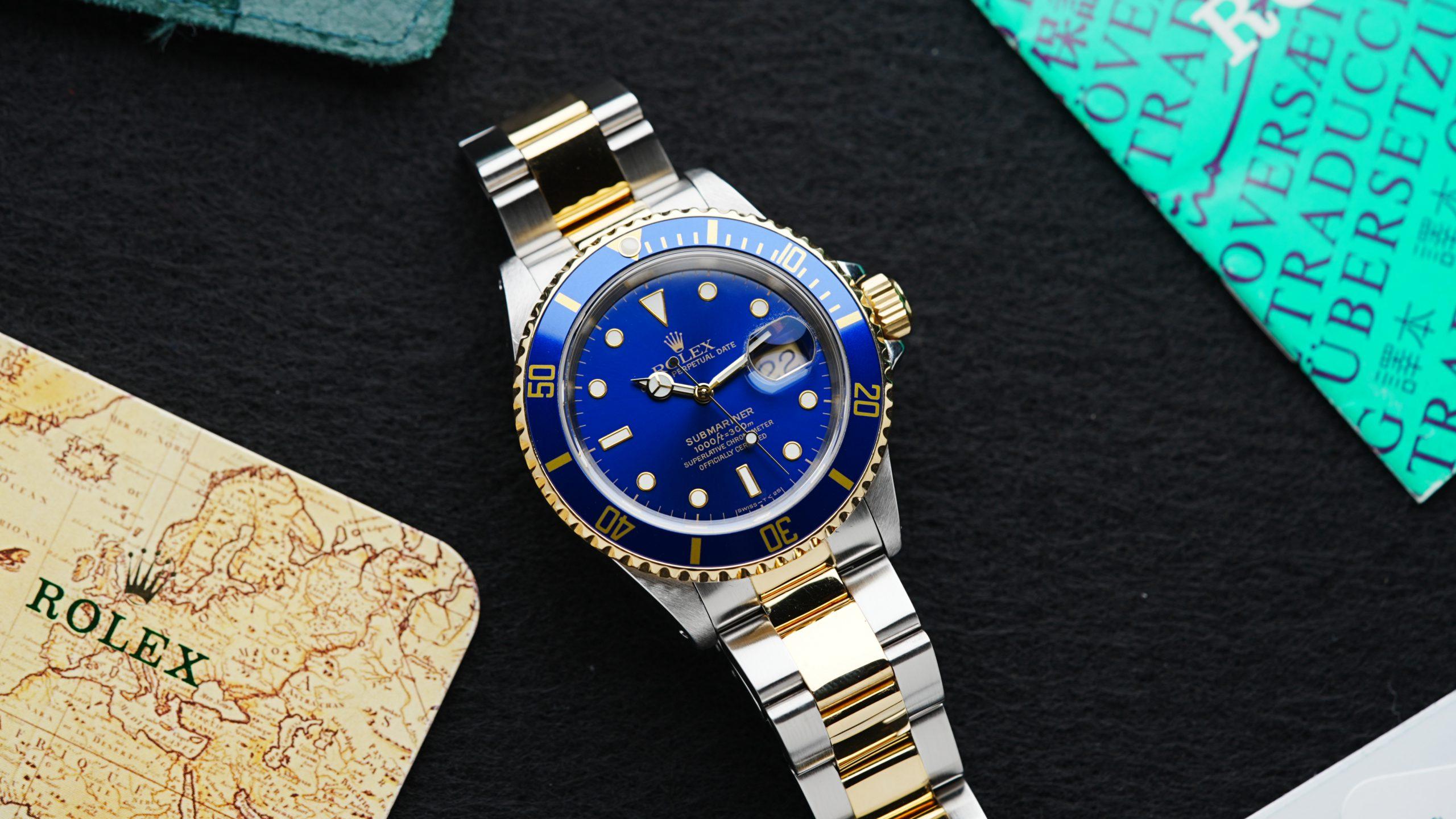 Rolex Submariner Date Two Tone Blusey 1991 featured beside original Rolex papers.