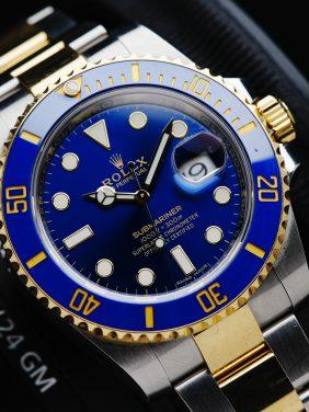 Rolex Submariner Blusey Two Tone Ceramic watch with camera in background.