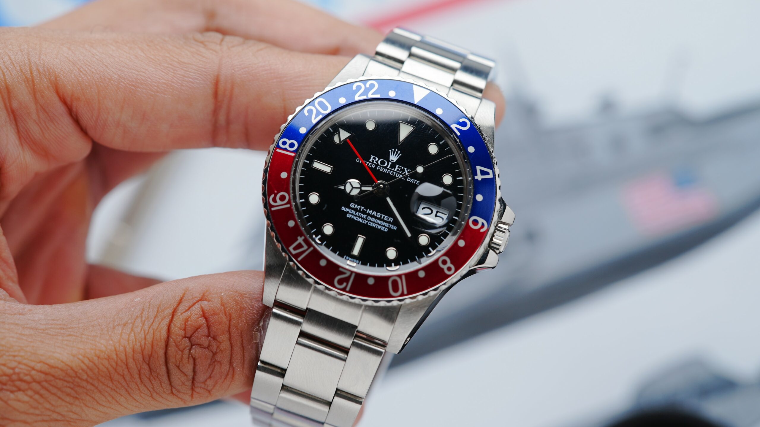 Rolex GMT-Master Pepsi watch held with fingers.