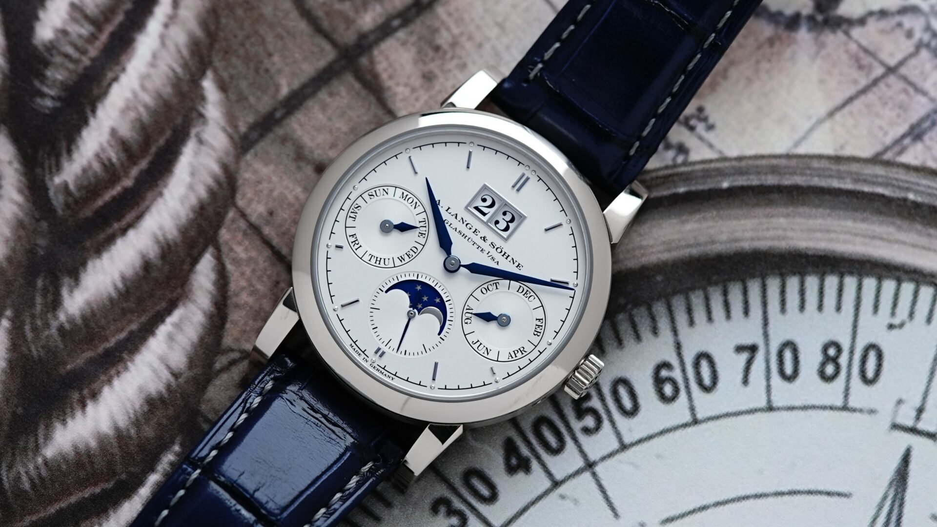 A. Lange & Söhne Saxonia Annual Calendar watch pictured with compass paper image in background.