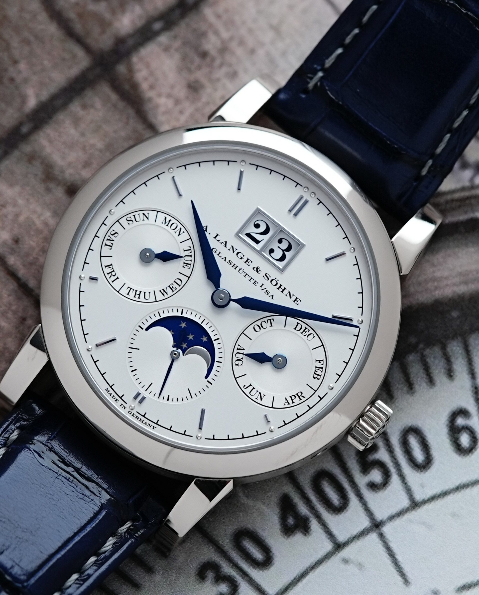 A. Lange & Söhne Saxonia Annual Calendar watch pictured with compass paper image in background.