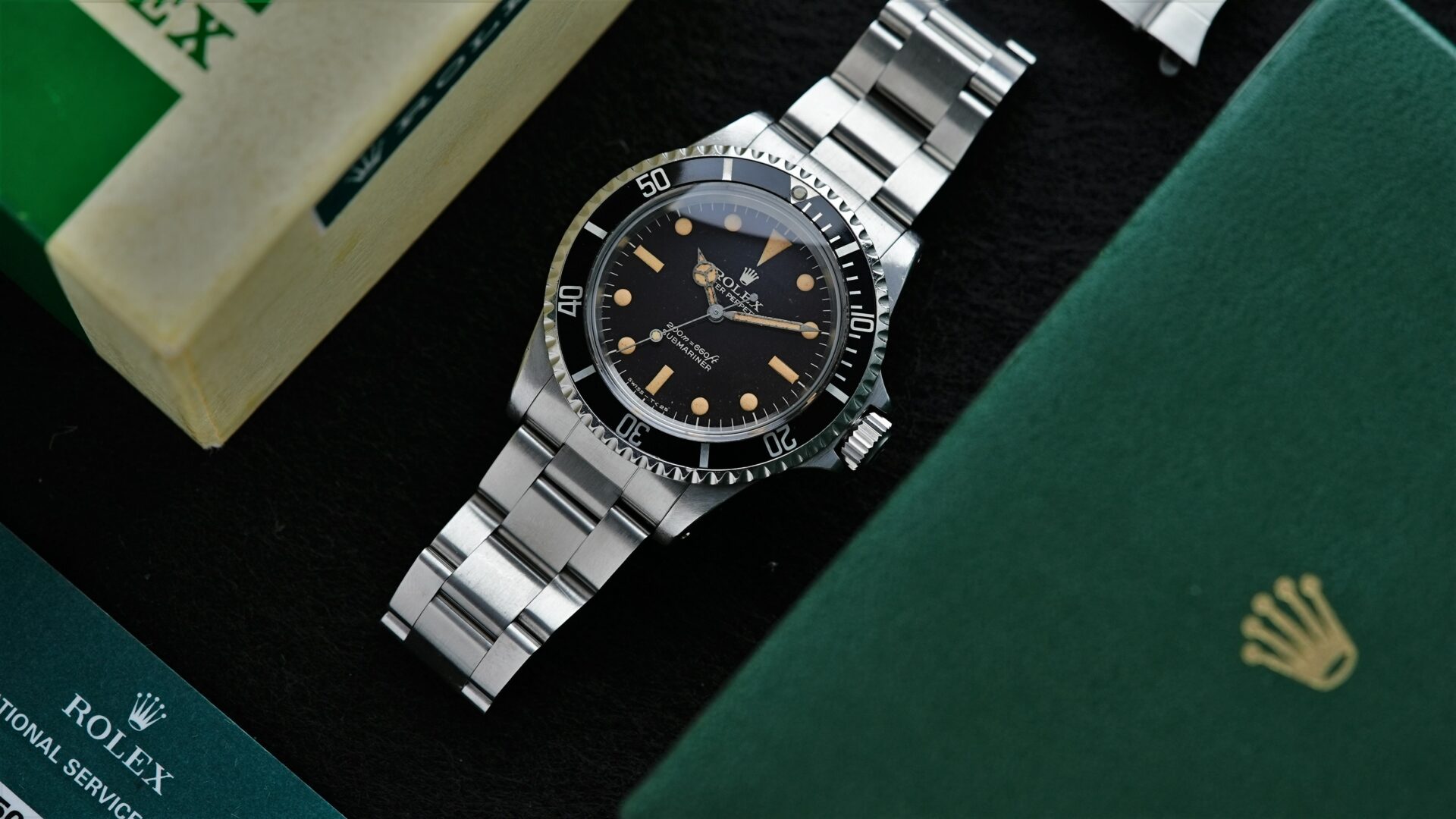 Rolex Submariner 5513 Bart Simpson Tropical Dial Original Patina Unpolished watch setting beside box and papers.