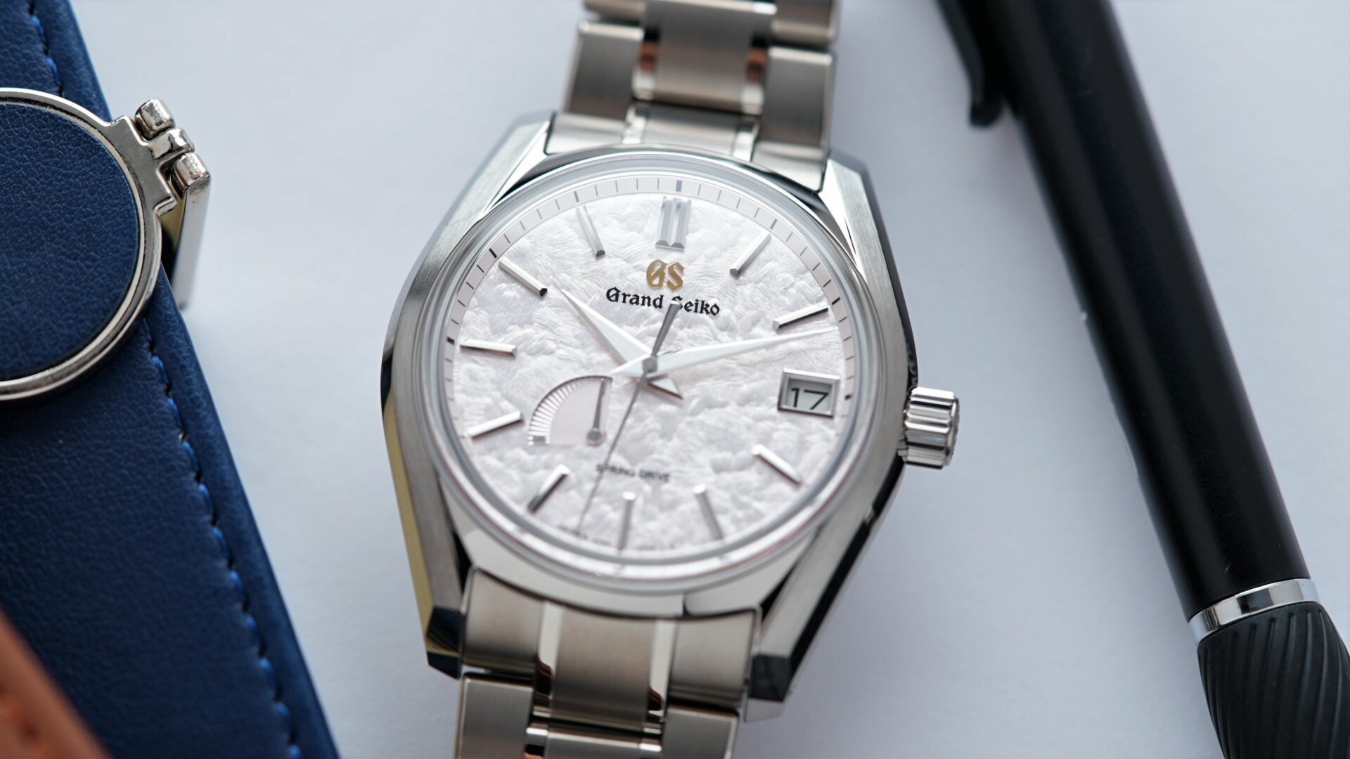 Grand Seiko Heritage Collection Seasons 'Spring' SBGA413 watch on display with notebooks and pen in background.
