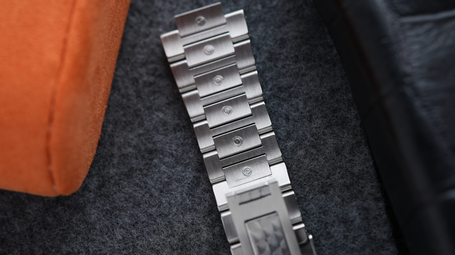 Steel bracelet on display beside orange cushion for the IWC Ingenieur Automatic 40MM 2021 On Bracelet & Extra Orange Rubber watch IW357002.