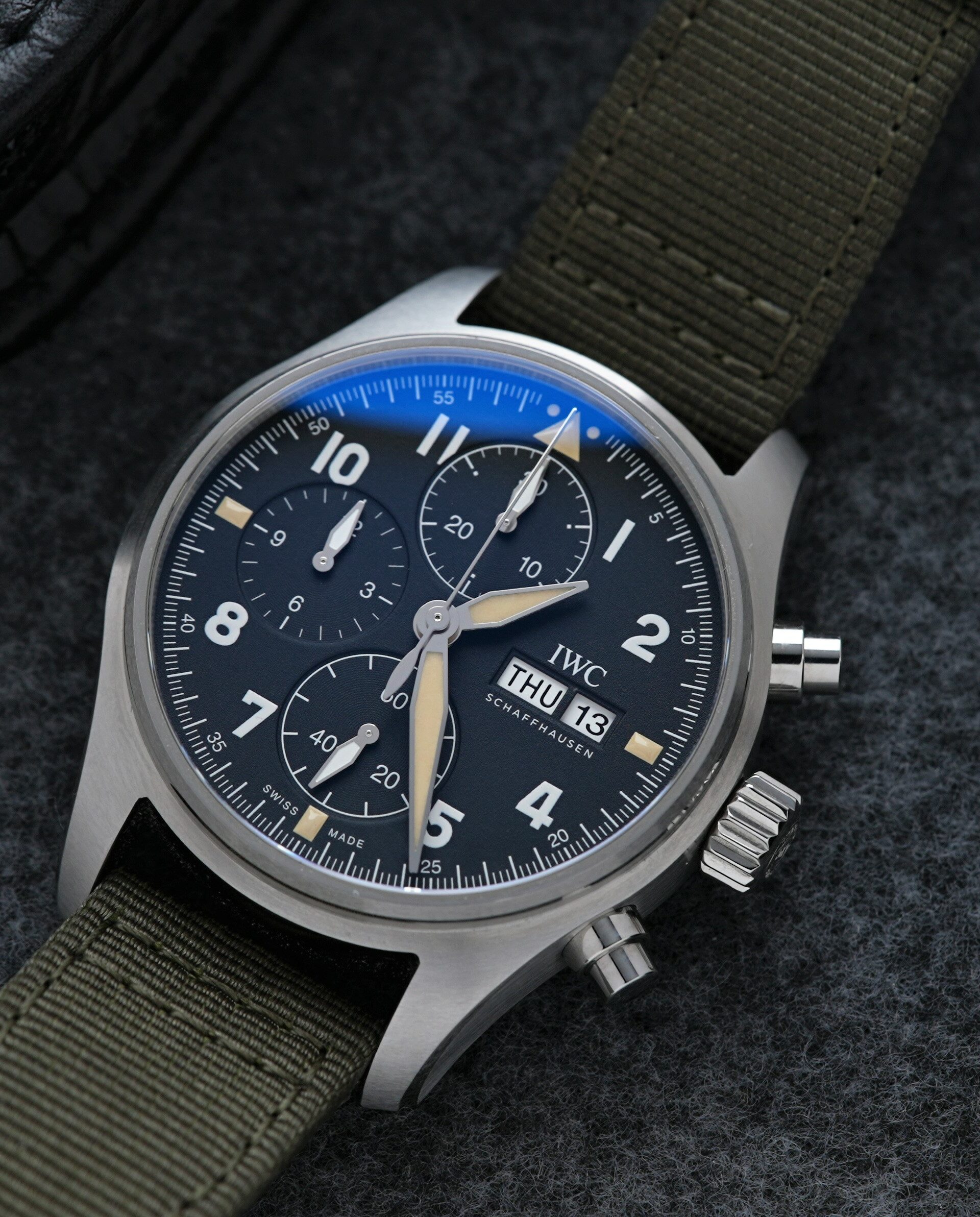 IWC Pilot Spitfire Chronograph 41MM IW387901 wristwatch on display with loop in background.