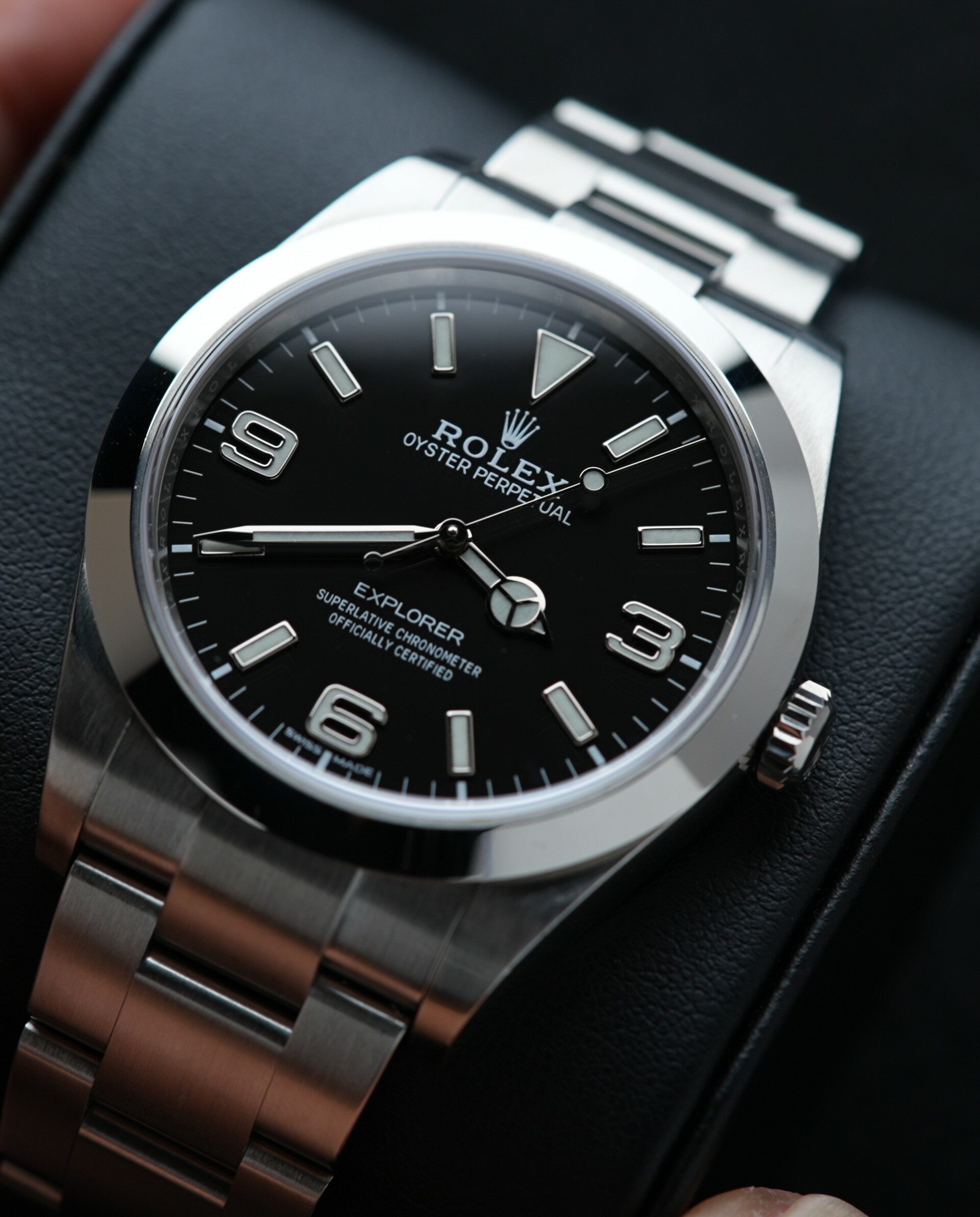 Rolex Explorer 214270 39mm watch being held while on cushion.