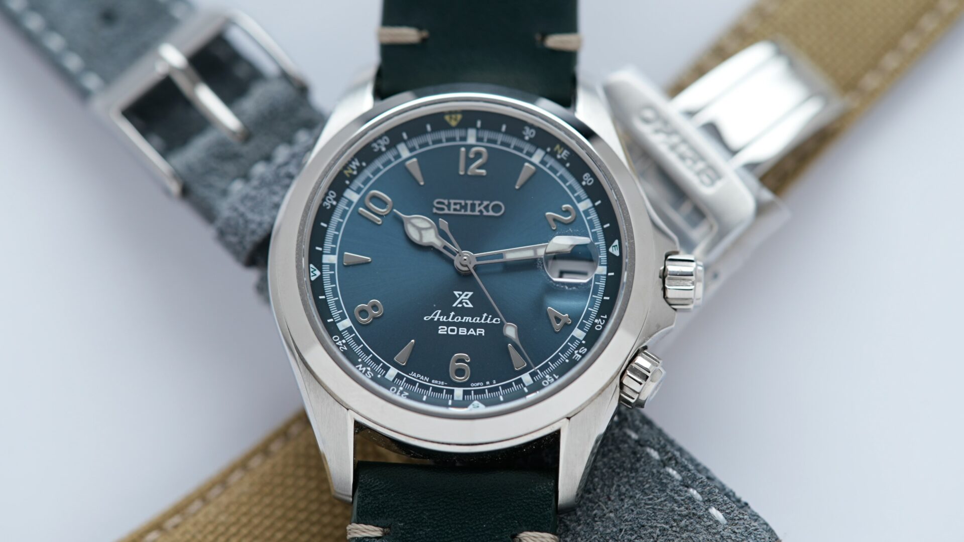 Seiko Alpinist Limited Edition Alpinist Mountain Glacier SPB199J1 watch on display along with two additional straps in the background.